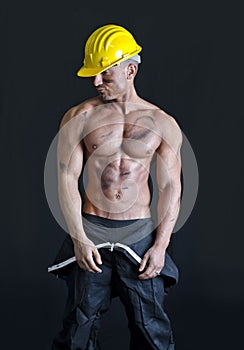 Shirtless muscular construction worker wearing coverall and hardhat