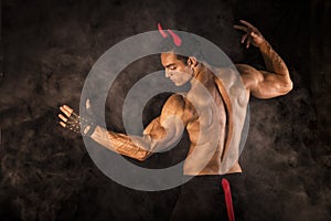 Shirtless muscular male bodybuilder dressed with devil costume