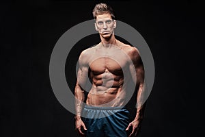 Shirtless muscular male over dark background.