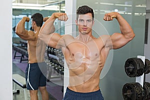 Shirtless muscular man flexing muscles in gym