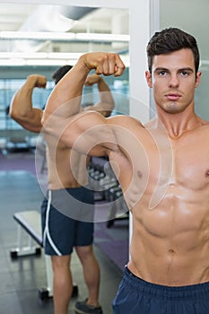 Shirtless muscular man flexing muscles in gym