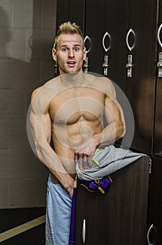 Shirtless muscular young male athlete in gym bathroom