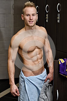 Shirtless muscular young male athlete in gym dressing room