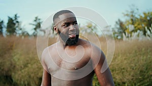 Shirtless runner standing in park after jogging. Sportsman looking away on road