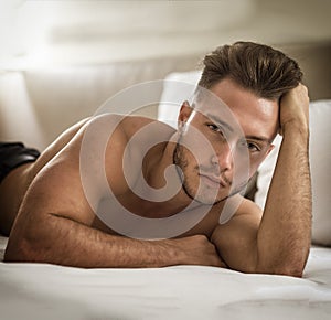 Shirtless sexy male model lying alone on his bed