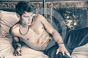 Shirtless male model lying alone on his bed