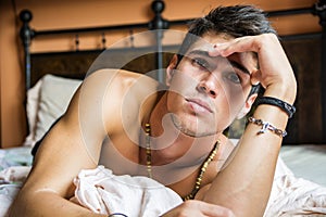 Shirtless male model lying alone on his bed