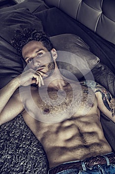 Shirtless male model lying alone on his bed