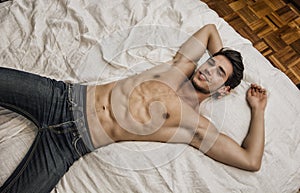 Shirtless male model lying alone on his bed photo