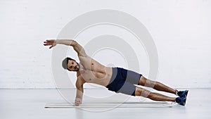 shirtless sportsman doing side plank exercise