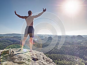 Shirtless sportsman raised arms to greeting nature