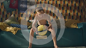 Shirtless teenage boy holds a football in his hands prepared for a soccer match