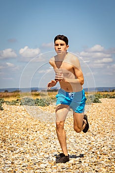 Shirtless teenage boy running on a beach