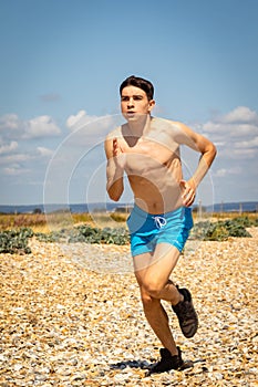 Shirtless teenage boy running on a beach