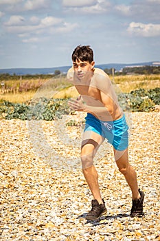 Shirtless teenage boy running on a beach