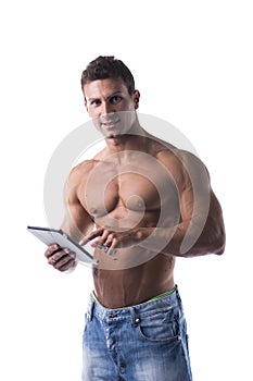 Shirtless young male bodybuiler holding ebook reader or tablet PC