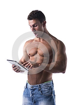 Shirtless young male bodybuiler holding ebook reader or tablet PC