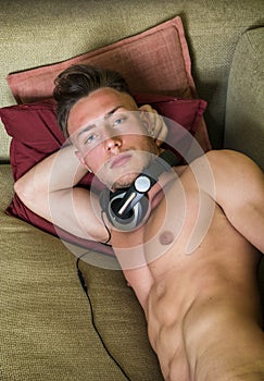 Shirtless young man on couch with headphones