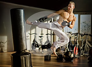 Shirtless young man doing flying kick