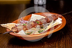 Shish kebab of beef, pork or lamb on a skewer lies on a plate in a restaurant