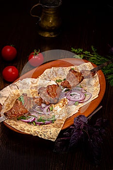 Shish kebab of beef, pork or lamb on a skewer lies on a plate in a restaurant