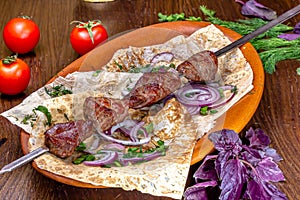 Shish kebab of beef, pork or lamb on a skewer lies on a plate in a restaurant