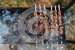 Shish kebab from a pork neck on skewers is prepared on coals in the grill