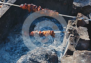 Shish pork meat on the open fire. Handmade barbecue place from stones and bricks. Summer tasty food