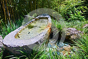 Shishi odoshi on stone canoe with colorful stone cobblestone path in Japanese Tea Garden