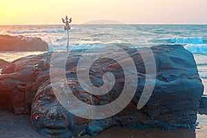 Shiva Face Rock Carving and Trident totem on Vagator Beach, Goa, India. Beautiful sunset background. Northernmost beach of Bardez