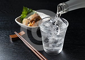 Shochu and nibbles set against a black wood grain background