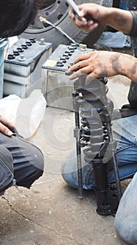Shock absorber replacement by Asian mechanic, Service industry transportation, background are battery and tire wheel