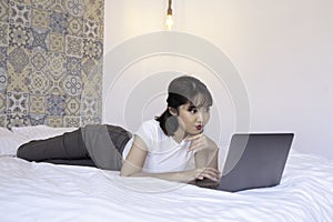 Shock asian beautiful girl work the laptop in the bed. Work from home concept