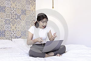 Shock asian beautiful girl work the laptop in the bed. Work from home concept