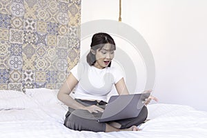 Shock asian beautiful girl work the laptop in the bed. Work from home concept