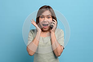 Shock / surprise and wow concept. Portrait of shocked asian woman looking in mobile phone and being surprised or astonished.