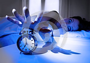 Shock upset young woman at home in bed not wanting to wake up turning off her alarm clock photo