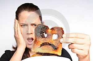 Shock woman holds a burnt slice of toast