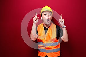 Shock Young asian man worker is surprised and shouting wow with pointing above with his hand isolated on red background