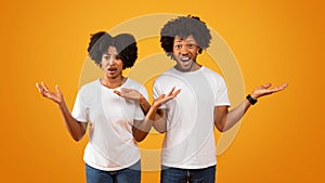 Shocked african american couple gesturing and grimacing on yellow