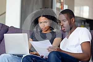 Shocked African American couple receiving bad news, reading letter