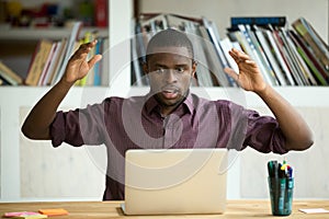 Shocked african american office worker looking at laptop screen.