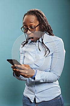 Shocked african american woman with touchscreen smartphone device astonished by received messages.