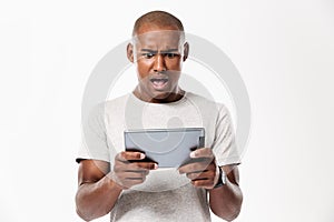 Shocked african man using tablet computer