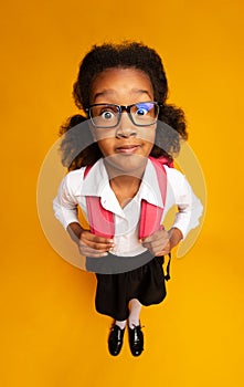 Shocked African School Girl Looking At Camera Standing Over Yellow Background