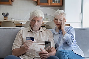 Shocked aged couple overspending money online using credit card phone