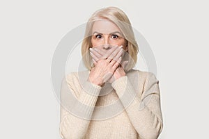 Shocked aged female covering mouth with hands feel scared