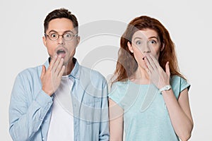 Shocked amazed couple covering mouth with hands looking at camera