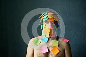 Shocked amazed man with colorful sticky notes all over his face and body