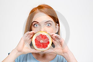 Shocked amusing lady holding grapefruit half in front of mouth